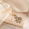 Macro shot of a spiral shell sun pendant in silver and gold on a beige stone - Spiral Sun Conch (JJN0175)