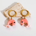Detailed close-up of pink enamel dolphin earrings on a textured natural stone base - Pink Dolphin
