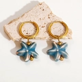 Detailed close-up of gold hoop earrings with blue ceramic starfish charms on stone - Starfish