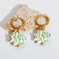 Detailed view of colorful fish ceramic earrings on a natural stone display - Green Fish