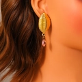Golden water drop earrings with textured metal and pink marquise stone on a model - Gold Threaded Olive Shape With Pink Gemstone Style (E1690)