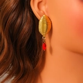 Close-up of gold textured metal earrings with red marquise stone on a model - Gold Threaded Metal With Red Marquise Gemstone Style (E1694)