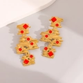 Detail view of vintage gold earrings with red enamel inserts on a minimalist stone display - Gold Red Contrast Vintage Abstract Art Style (E1681)