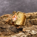 Dettaglio macro di un anello largo in titanio dorato con gemma rosa e texture vintage - US 7 / Oro Zirconia Rosa