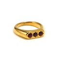 Dettaglio macro di anello placcato oro 18k con tre zirconi rossi incastonati a stella - Oro con gemma rosso granato