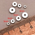 Vista macro de cuentas espaciadoras plateadas de 3mm a 6mm sobre tela gris rugosa - 3mm / Platino