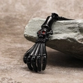 Close-up of a punk skull hand pendant in matte black finish with red gemstone eyes - Black Pendant (No Chain)