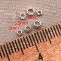 Macro view of 2mm 2.5mm and 3mm silver metal positioning beads on textured fabric - 2mm/Aperture 1.3mm - Crimp Beads / Thick Silver