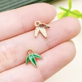 Bamboo leaf pendants in gold finish and green enamel displayed on fingertips - Green Enamel Bamboo and Leaf