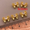 Macro shot of 18K gold plated bow beads with pink zirconia for jewelry making - Heart-Shaped Bowknot Spacer Bead (T435) / 8x10mm (Hole 2mm, Thickness 5mm) / 1 Piece - Gold With Light Purple Zirconia
