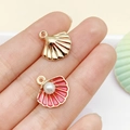 Shell shaped metal pendant and pink enamel charm with pearl in hand view - Deep Pink