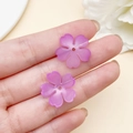 Mano sosteniendo dos pétalos de cerezo acrílicos púrpuras para creación de joyería DIY - Degradado Rosa Transparente (22018) / 1 Pieza/Paquete (18x18mm)