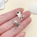 Silver octopus alloy charm for DIY jewelry showing front and back texture on a finger - Octopus Style
