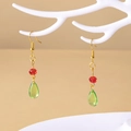 Detail of Howl's Moving Castle green teardrop earrings with red beads on a jewelry stand - Earring Hooks