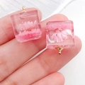 Square resin pendant with embedded pink dried flowers and a gold metal ring loop - Pink Cube (19177)