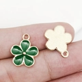 Gros plan de pendentifs tournesols en émail vert sur le bout des doigts avec détails dorés - Fleur en Email (17538) / 14x17mm
