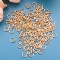 Macro di anellini aperti dorati per creazione gioielli fai-da-te su sfondo blu - oro kc