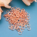 Macro di anellini aperti in oro rosa per gioielli fai da te con sfondo floreale - Oro rosa