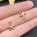 Golden starfish charms for DIY jewelry making shown in hand for scale reference - KC Gold Marine Small Starfish Style (11594)