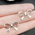 Antique silver bow tie alloy pendant connector shown on a finger for scale and detail - Antique Silver Bow Style (11246)