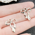 Ciondolo a fiocco in argento antico mostrato sulla mano con sfondo nero strutturato - Stile Fiocco con Laccio Argento Antico (19433)