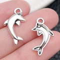 Dijes de delfín plateados para joyería DIY mostrados en la mano para escala de tamaño - Delfín Océano Plata Antigua (17314)