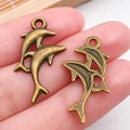 Colgantes de delfín en bronce para joyería DIY, acabados lisos y con texturas finas - Dos Delfines Bronce Antiguo (20726)