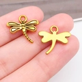 Colgantes de libélula en oro antiguo para joyas DIY mostrados en la mano - Estilo Libélula Oro Antiguo (20168) / 16.6x15mm
