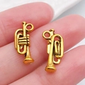 Dijes de trompeta en oro vintage para joyería artesanal mostrados en las yemas - Trompeta (20884)