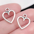 DIY sieraden benodigdheden met mat zilveren hart hangers op de vinger getoond - Antiek Zilveren Opengewerkt Hart (13336)