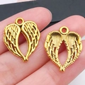 Paar gouden holle hart engelenvleugel bedeltjes voor DIY sieraden op een vingertop - Antiek Gouden Gevleugeld Hart (19989)