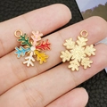 Schneeflocken Anhänger in Goldoptik und buntem Emaille auf schwarzem Lederhintergrund - Mehrfarbige Emaille Weihnachts-Schneeflocke / 24x19mm