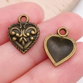 Antieke bronzen hartbedeltjes voor DIY sieraden maken getoond op vingertoppen - Antiek Brons Hart (19947)