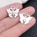 Colgantes de mariposa hueca plateados para bisutería DIY mostrados en mano - Estilo Mariposa Plata Brillante (20189) / 16.4x16mm