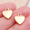 Gouden hartvormige bedeltjes voor DIY sieraden maken getoond op een vingertop - KC Gouden Hart (19973)