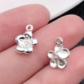 Zilverkleurige bloemenhangers voor DIY-sieraden maken getoond op de vingertoppen - Bright Silver Flower Stamen (12x9mm)