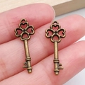 Colgante llave trébol corazón bronce vintage sobre mano para joyería artesanal - Llave Bronce Antiguo (20990)