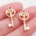 Set de dos colgantes de llave dorados con símbolo de trisquel para joyas DIY - Llave Oro KC (20999)