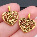 Vintage gouden hartbedeltjes met filigraanpatroon getoond op de vingertop voor schaal - Antiek Gouden Hart (10255)