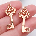 Colgantes de llave hueca en oro rosa retro para joyas DIY mostrados en mano - Llave Oro KC (21005)