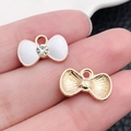 Golden bow-shaped alloy pendant with white enamel finish and small sparkling rhinestone - Crystal Bowknot 14.6x9mm (10997)
