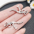 Vintage silver dinosaur skeleton pendants for DIY jewelry making held in hand - Antique Silver Skeleton Dinosaur Style (18580)