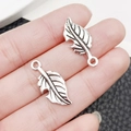 Pair of vintage silver leaf alloy pendants for DIY jewelry making shown between fingers - Antique Silver Leaf Style (6004)