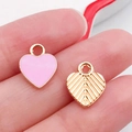 Pink heart pendant with gold edges and engraved back shown on a fingertip for DIY jewelry - Pink Enamel Heart Shape Style