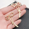 Golden bow-shaped alloy charms for DIY bracelets held in hand to show size and scale - Long Bowknot (45x27mm)