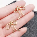 Golden bow-knot charms for DIY jewelry making held in hand for size demonstration - Small Bowknot (25x22mm)