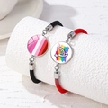 Detail von handgewebten LGBTQ+ Pride Armbändern mit Regenbogen-Anhängern auf weißen Säulen - Lesbian Pride und Regenbogenhintergrund Weibliches Symbol (Stil 2)