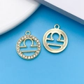 Golden Libra zodiac pendants with crystals and radial patterns on a blue background - KC Gold Libra