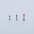 Detaillierte Makroansicht von drei regenbogenfarbenen Labret-Steckern aus Edelstahl - 6mm / bunt