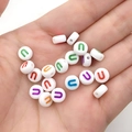 Handbeeld van witte ronde acryl kralen met kleurrijke U-print voor DIY-sieraden maken - Veelkleurige Letter U